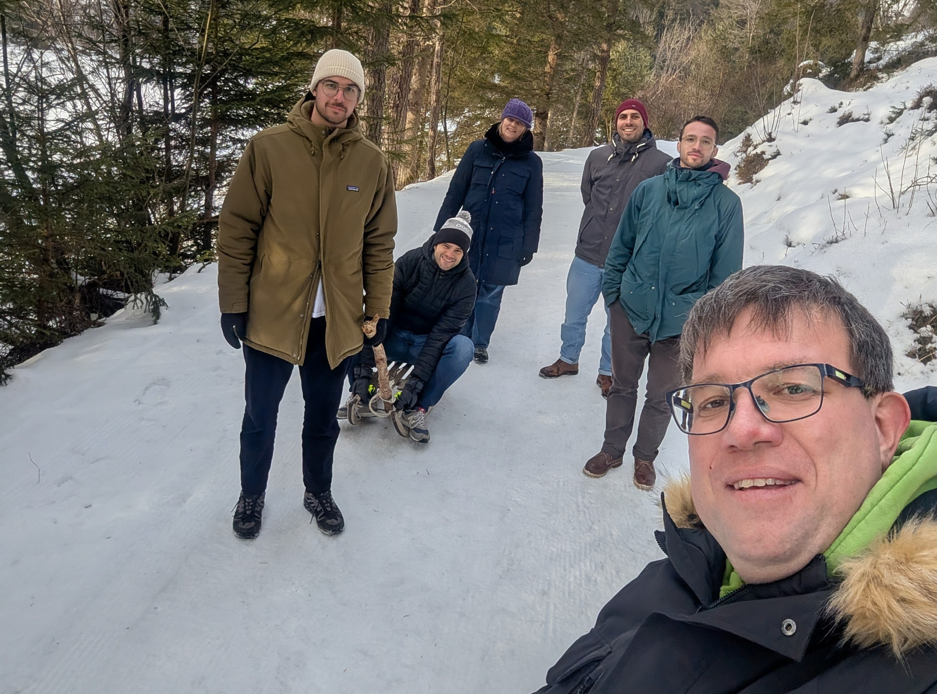 Teammitglieder mit einem Schlitten auf einem verschneiten Waldweg