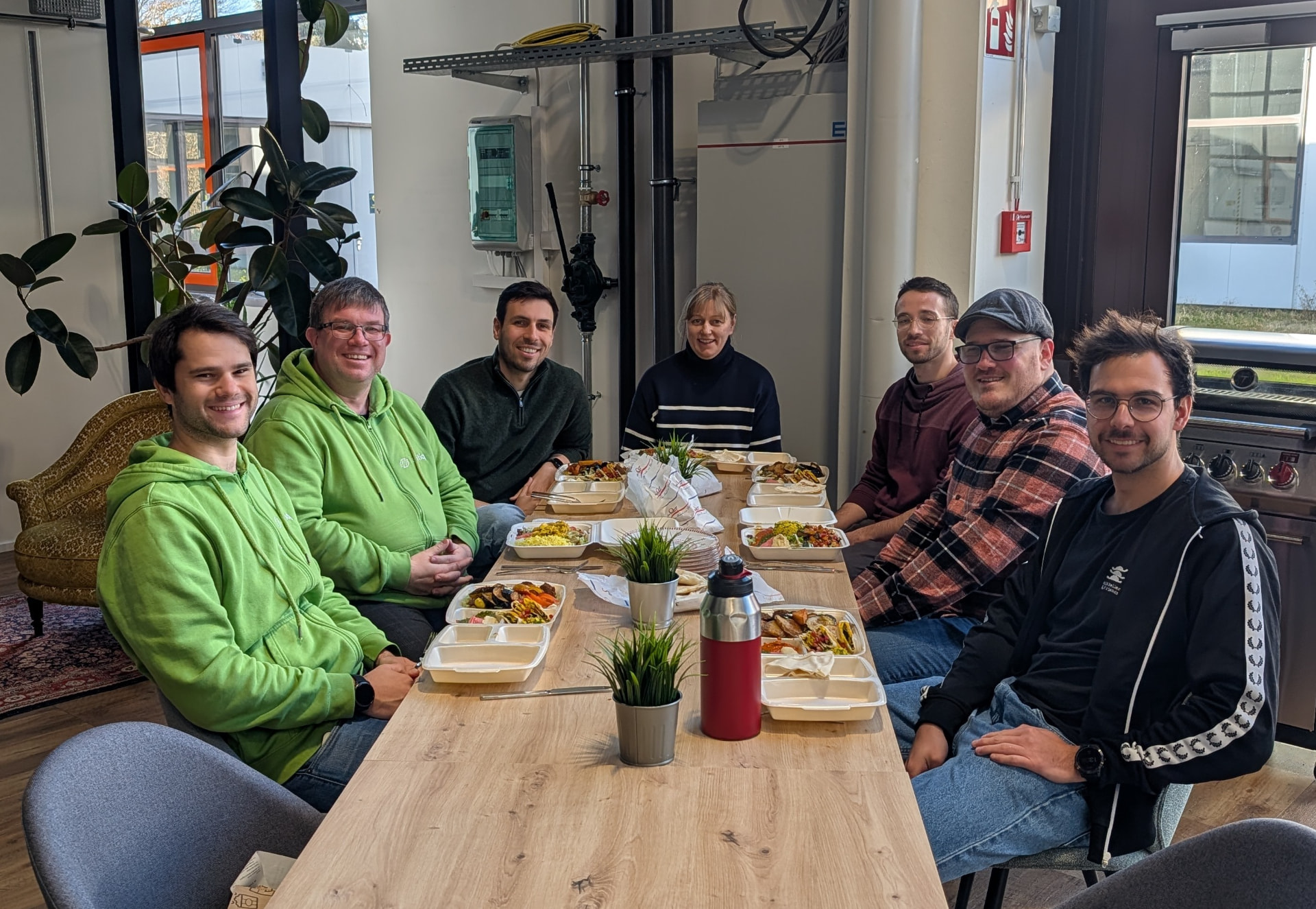Das alitiq-Team beim gemeinsamen Mittagessen an einem langen Holztisch