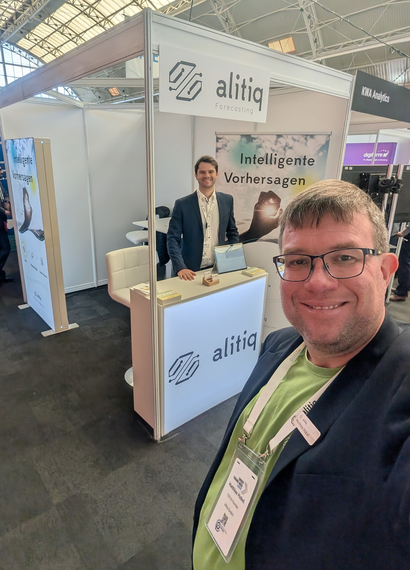 Matthias Habel vor dem alitiq-Messestand, im Hintergrund Daniel Gröger